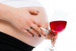 Mujer embarazada con cigarro y taza de vino en las manos
