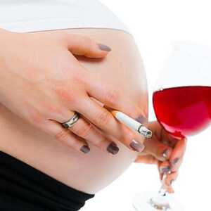 Mujer embarazada con cigarro y taza de vino en las manos