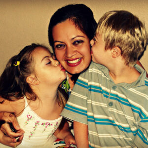 Una madre junto a sus dos hijos con Síndrome de Down.