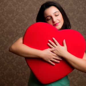 Mujer abrazando un corazón de peluche.