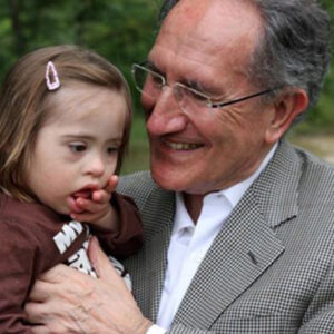 Doctor con una nena con Síndrome de Down en los brazos.