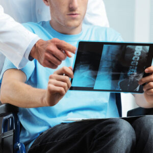 Hombre en silla de ruedas viendo una radiografía.